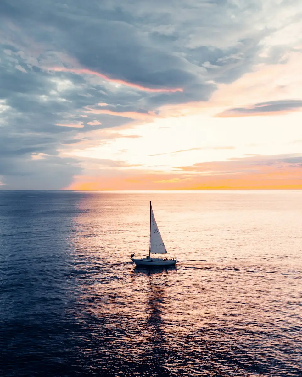 white sailboat on sea during sunset